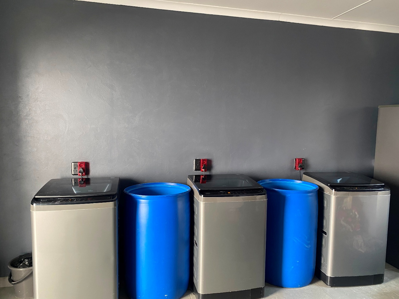 Laundry room with washing machines and water storage drums