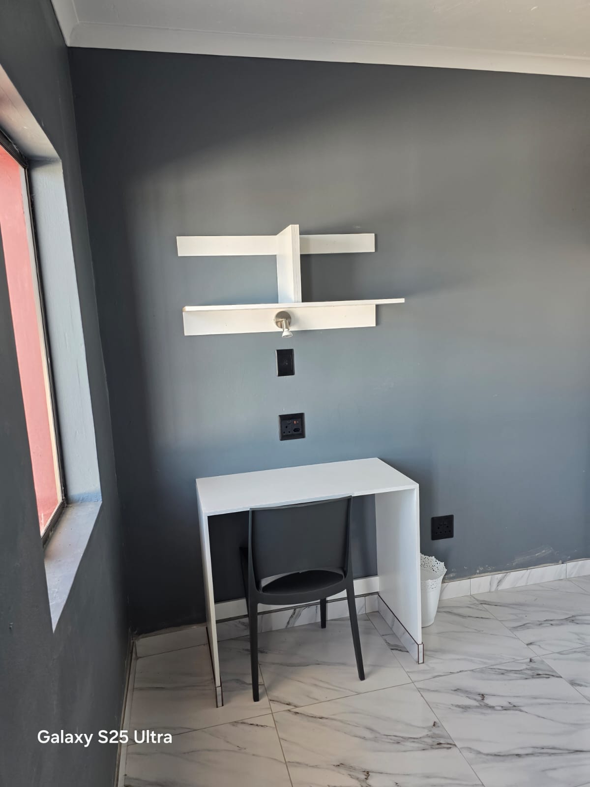 Study desk and wall shelving with power points inside a student room