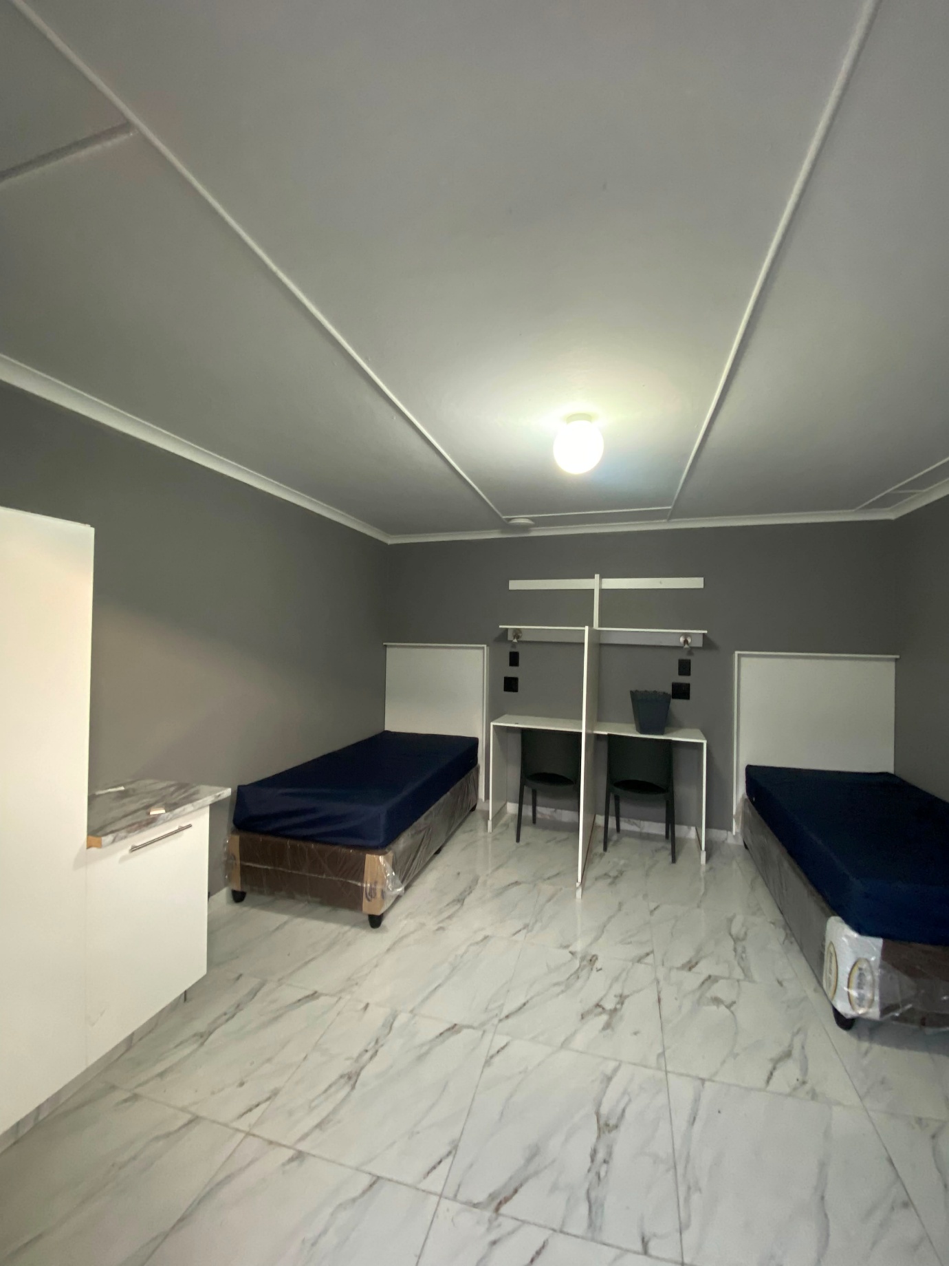 Furnished twin student room with beds, study desks and built-in cupboards